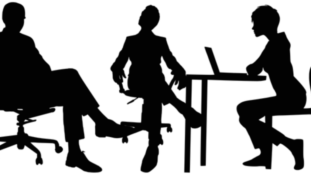 Concentric Advisors Interview A group of professionals conducting an interview in a modern office setting, with one candidate being interviewed by a panel of interviewers. The image conveys a formal and professional atmosphere, highlighting the interview process at Concentric Advisors.