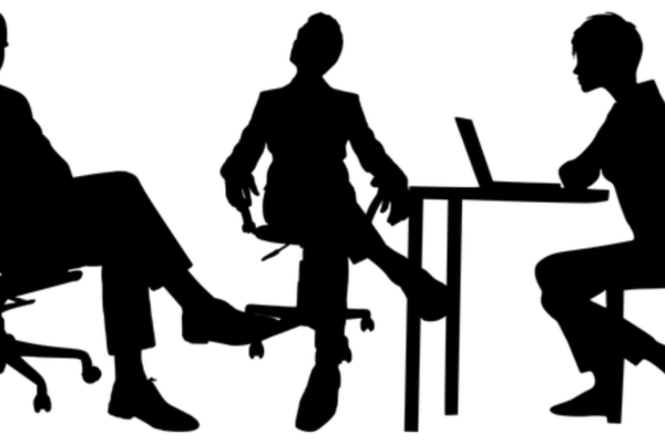 A group of professionals conducting an interview in a modern office setting, with one candidate being interviewed by a panel of interviewers. The image conveys a formal and professional atmosphere, highlighting the interview process at Concentric Advisors.