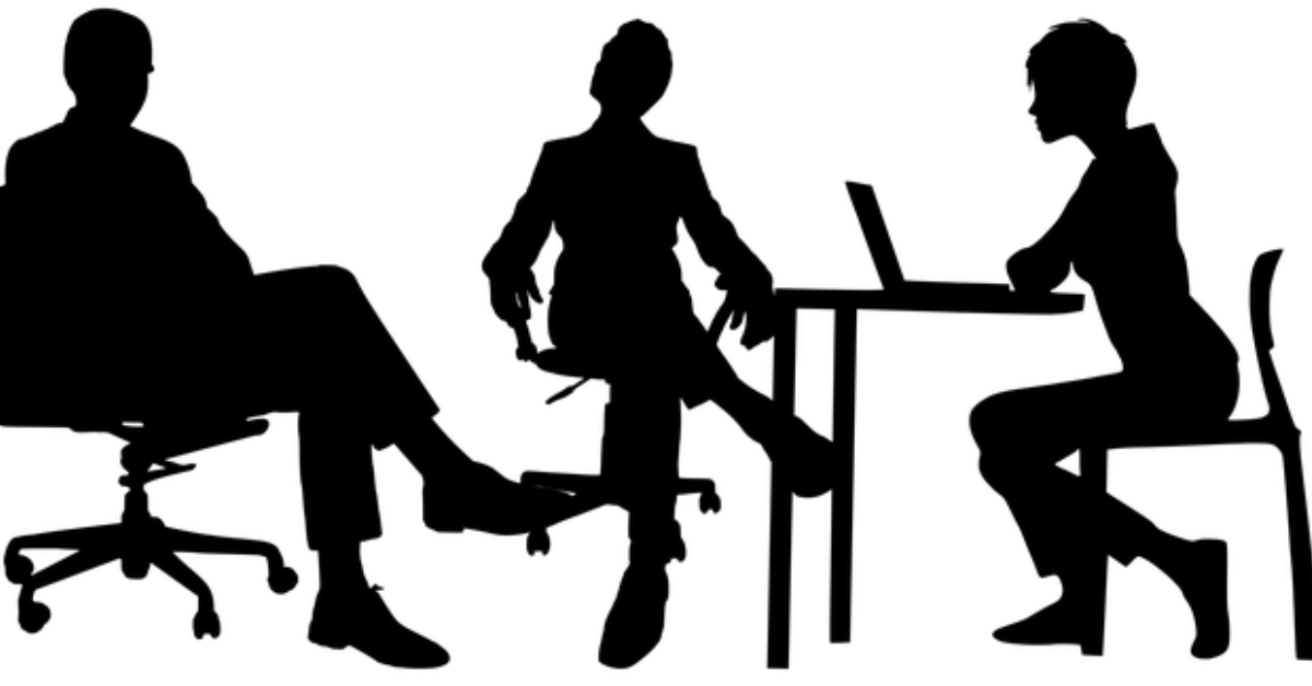 A group of professionals conducting an interview in a modern office setting, with one candidate being interviewed by a panel of interviewers. The image conveys a formal and professional atmosphere, highlighting the interview process at Concentric Advisors.